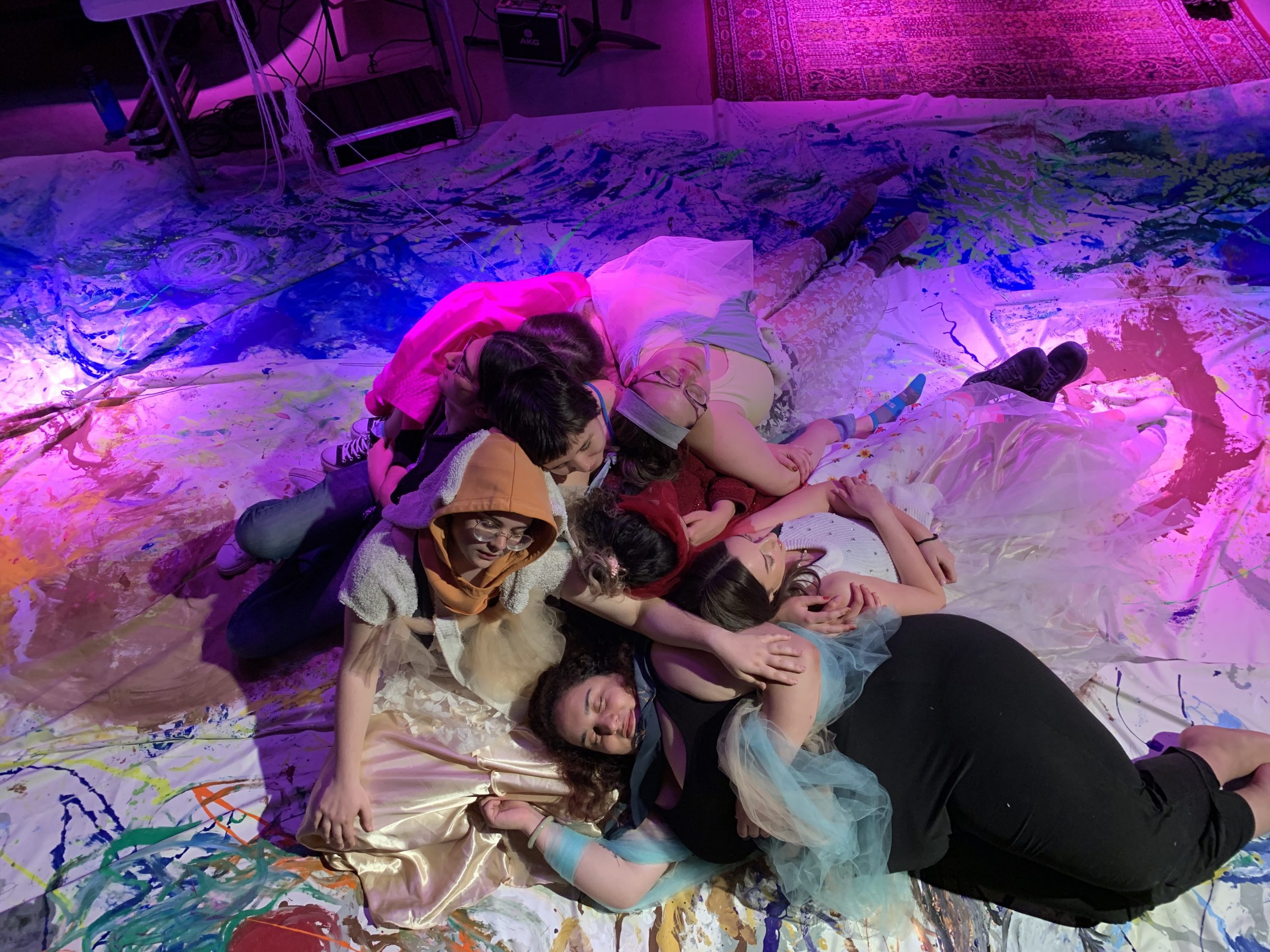 costumed women lie on a large painted canvas