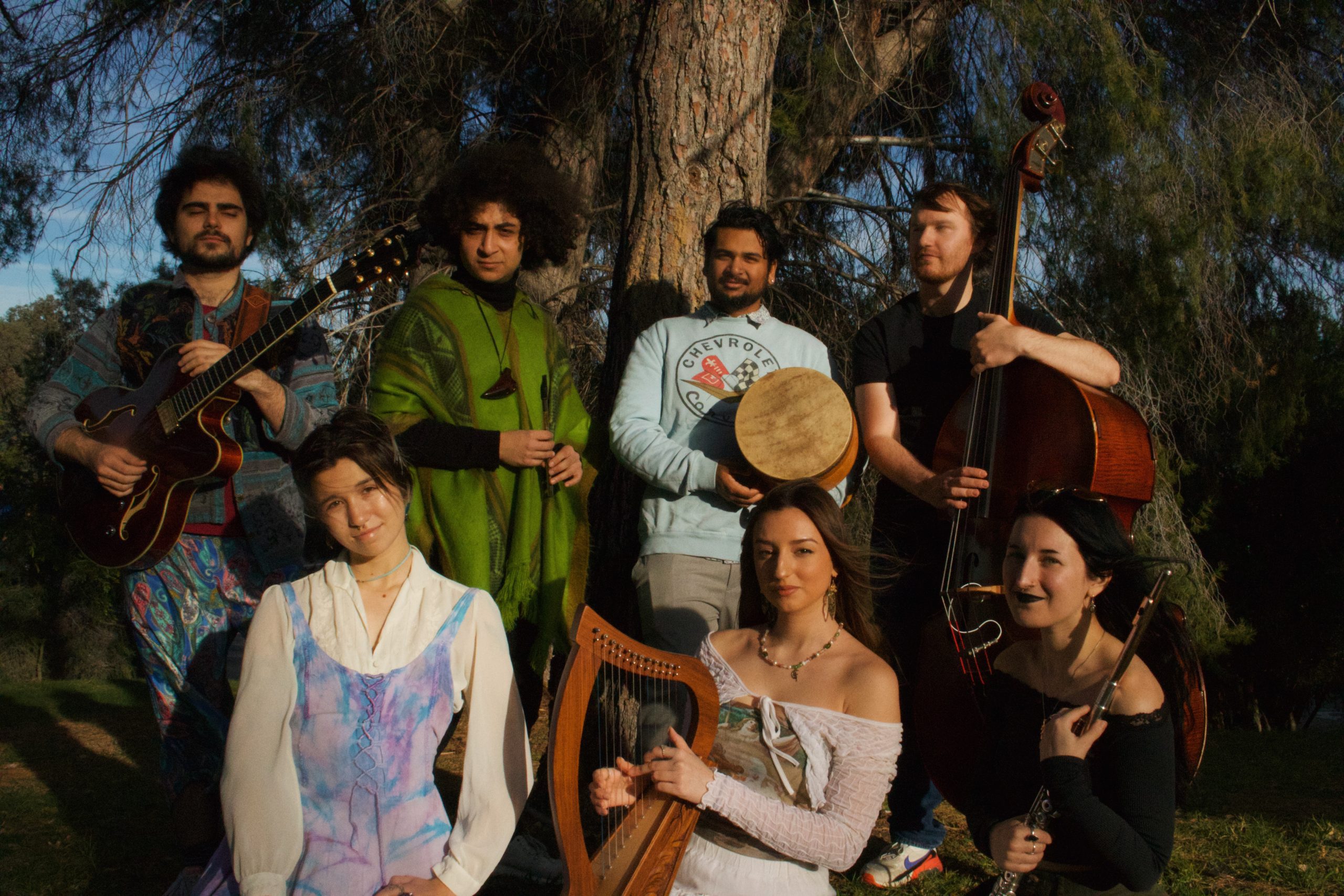 group of musicians pose in front of pine trees